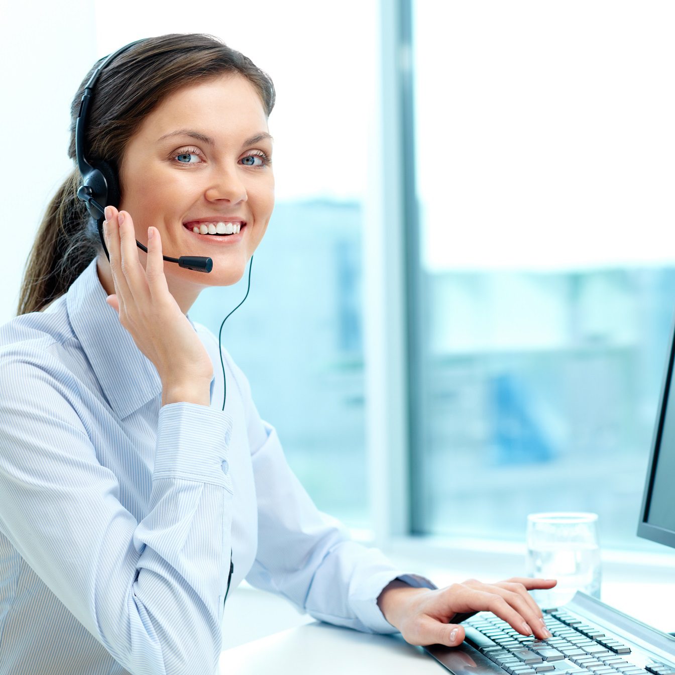 Portrait of young operator with headset looking at camera with friendly smile